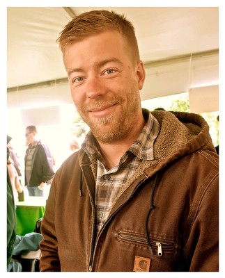Smiling man at Lodi Winegrape Commission event, wearing a brown jacket and plaid shirt.