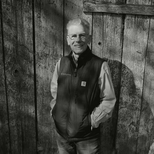 Smiling man in vest standing outdoors against wooden fence, representing Lodi Winegrape Commission.