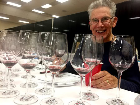 Smiling man at wine tasting with multiple wine glasses on table, promoting Lodi winegrapes and wine industry.