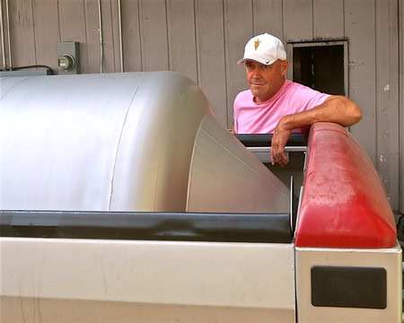 Man inspecting winegrape harvesting equipment at Lodi Winegrape Commission vineyard.