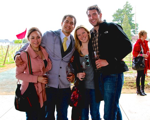 Group of four friends smiling and holding wine glasses at a wine event in Lodi, California.