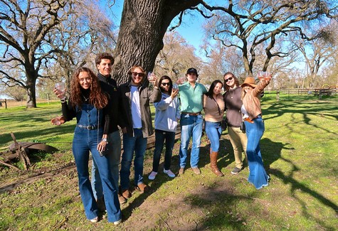 Group of people enjoying outdoor wine tasting at Lodi Winegrape Commission event.