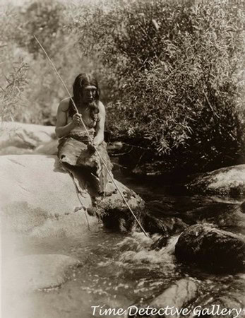Vintage photo of a woman fishing in a stream, surrounded by nature, from the early 20th century.