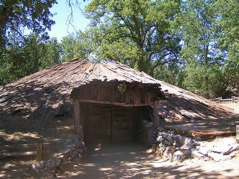 Traditional vineyard hut in Lodi, California, surrounded by lush trees and rustic stone walls.