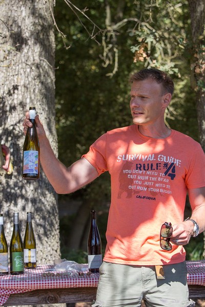 Man holding a wine bottle outdoors at a wine tasting event in Lodi, California.