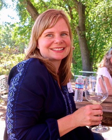 Woman enjoying wine tasting outdoors at a Lodi Winegrape Commission event.
