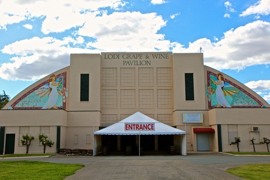 Exterior view of the Lodi Grape & Wine Pavilion with entrance tent and colorful murals on the building.