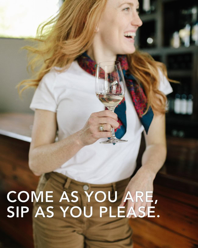 Woman enjoying wine at Lodi Winegrape Commission event, smiling and holding a glass of white wine.