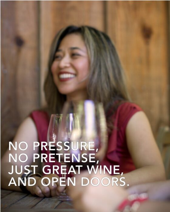 Woman enjoying wine tasting at Lodi Winegrape Commission event, smiling with glasses of wine.