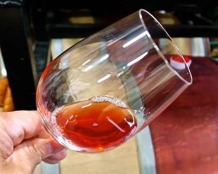 Close-up of a hand holding a glass of red wine with a blurred background.