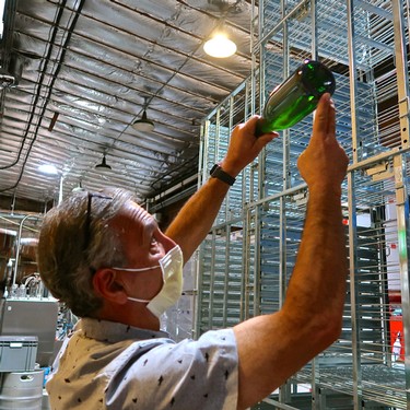 Man inspecting wine bottles in a warehouse at Lodi Winegrape Commission.