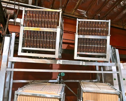 Winegrape harvesting equipment in a winery facility, showcasing stainless steel racks and machinery for grape processing.