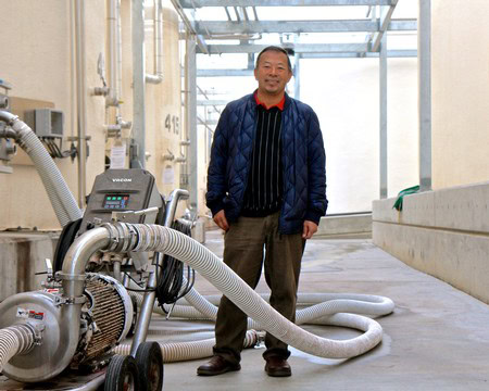 Man standing in a winery with grape processing equipment in Lodi, California.