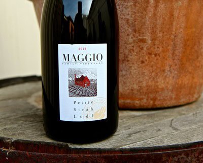 2014 Maggio Petite Sirah Lodi wine bottle with label on wooden surface.