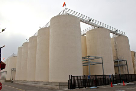 Large white storage tanks at a winery facility in Lodi, California, used for wine grape fermentation and storage.