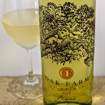Bottle of Oak Farm 2018 wine from Lodi Winegrape Commission with a glass of white wine.