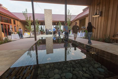 People attending a wine event at Lodi Winegrape Commission with a modern indoor setting and water feature.