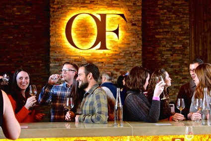Group of people enjoying wine tasting at Lodi Winegrape Commission event with warm lighting and brick wall background.