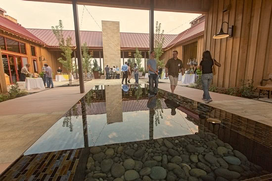 People attending a wine event at Lodi Winegrape Commission, with indoor and outdoor spaces and a reflective water feature.
