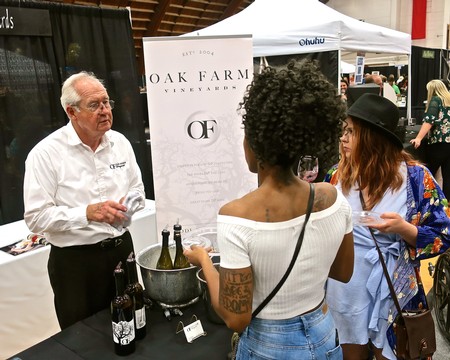 Wine expert discussing with attendees at Lodi Winegrape Commission booth during a wine event.
