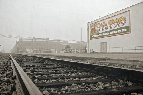 View of railroad tracks leading to Oak Ridge Winery tasting room in Lodi, California, with a large sign on the building.