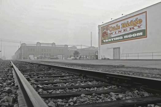 View of railroad tracks leading to Oak Ridge Winery tasting room in Lodi, California, with a large sign in the background.