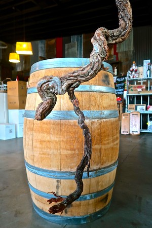 Artistic wine barrel with a twisted grapevine sculpture in a wine shop setting.