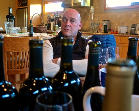 Man at wine tasting event with bottles of wine in foreground, Lodi Winegrape Commission focus.