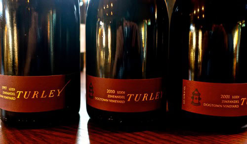 Close-up of three wine bottles from Zinfandel Vineyard in Lodi, showcasing vintage labels and dark glass bottles.