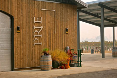 Exterior view of Lodi Winegrape Commission building with wooden siding and wine barrel decor.