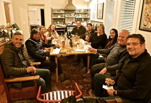 Group of people enjoying a dinner meeting at a restaurant, smiling and engaging in conversation.