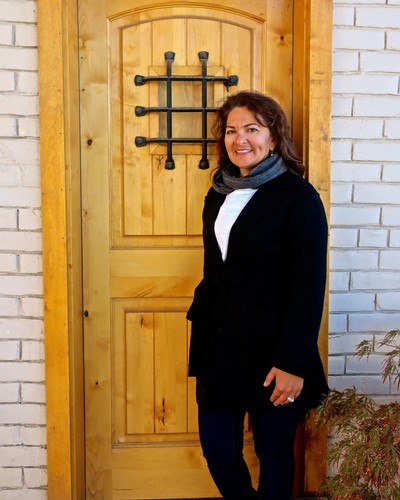 Woman standing outside Lodi Winegrape Commission office with wooden door and brick wall.