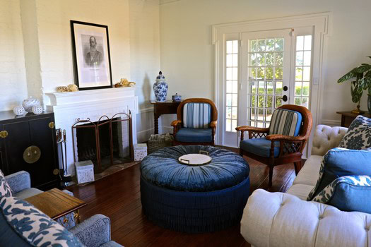 Elegant living room with vintage furniture, fireplace, and large windows letting in natural light.