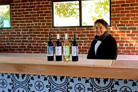 Woman smiling at wine bottles during tasting at Lodi Winegrape Commission event.