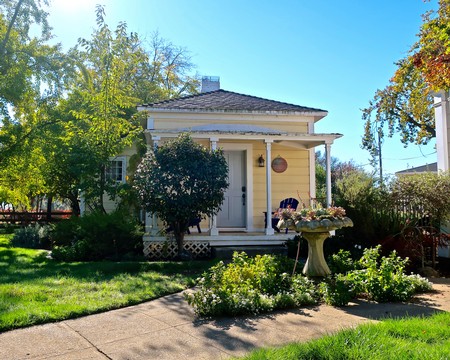 Beautiful small house with a garden, trees, and a decorative birdbath in Lodi, California.