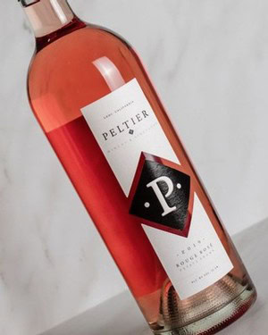 Lodi Winegrape Commission rosé wine bottle on a white surface, showcasing a sleek label and pinkish hue.