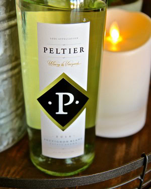 Close-up of a Peltier wine bottle from Lodi Winegrape Commission with a lit candle nearby.