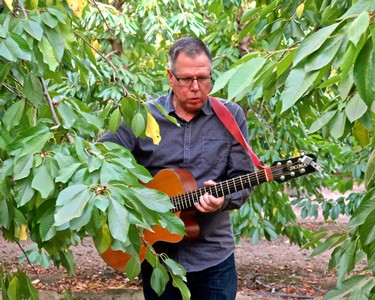 Grape grower playing guitar among lush grapevines at Lodi Winegrape Commission.