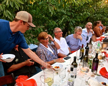 People enjoying a wine tasting event outdoors with wine bottles and glasses on a table.