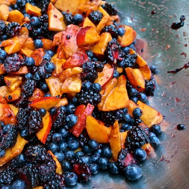 Colorful fruit salad with blueberries, peaches, and blackberries in a bowl.
