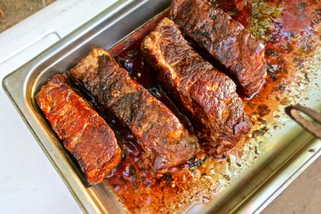 Tender, juicy barbecue ribs with a rich glaze served in a metal tray.