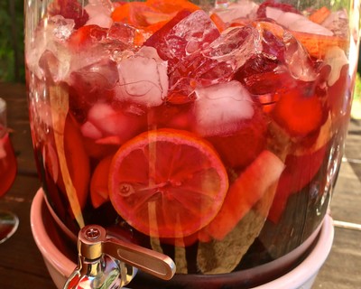 Fresh fruit infusion with citrus slices, berries, and herbs in a glass jar for wine or beverage flavoring.