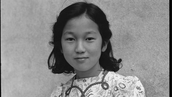 Black and white portrait of a young girl with wavy hair wearing traditional clothing.