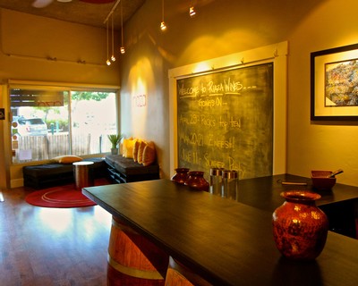 Interior view of a cozy wine tasting room with a chalkboard menu and decorative vases.