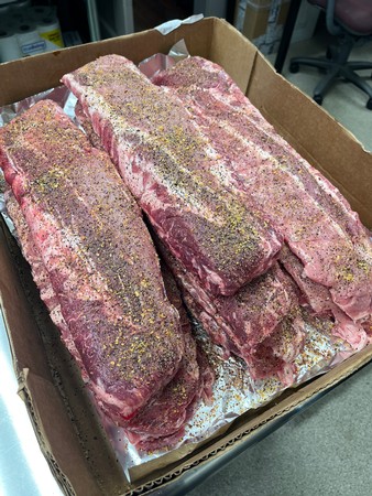 Raw beef ribs seasoned with spices in a cardboard box for wine grape production.