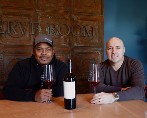 Two men enjoying wine tasting with a bottle of red wine at a winery.