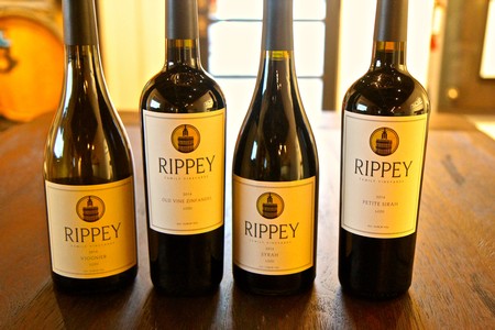 Four bottles of Rippey wine from Lodi Winegrape Commission on a wooden table.