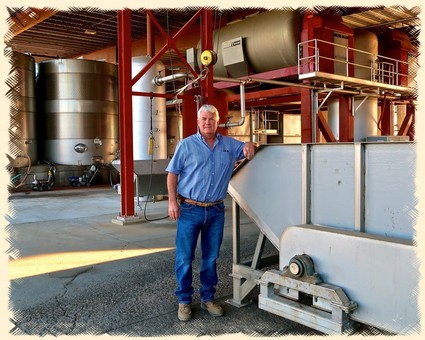 Man standing inside a winery with large tanks and equipment in Lodi, California.