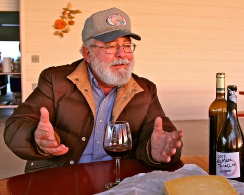 Elderly man with glasses and beard tasting wine at Lodi Winegrape Commission event.