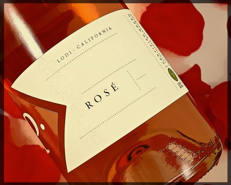 Close-up of a Lodi California Rosé wine bottle with a white label and red rose petals in the background.